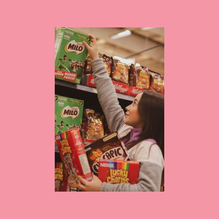 Nuori asiakas valitsee aamiaismuroja supermarketin hyllyltä, mikä havainnollistaa UGC-markkinoinnin asiakaslähtöistä näkökulmaa.