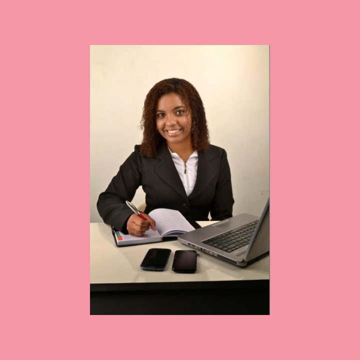 Ammattilainen suunnittelee sisällöntuotantoa kirjoittaen muistikirjaan kannettavan tietokoneen ja kahden älypuhelimen äärellä.