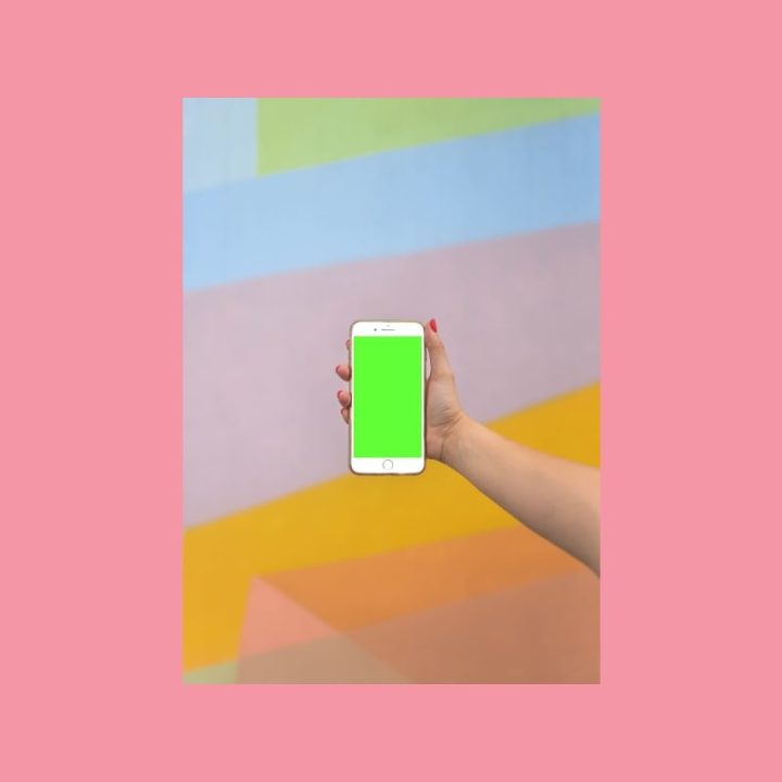Käsi pitelee älypuhelinta värikkäällä taustalla, korostaen SEO-sisällön mobiilikäyttöä.