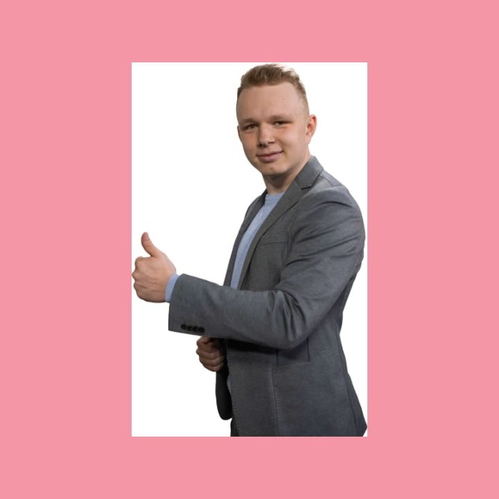 Hymyilevä mies harmaassa bleiserissä näyttää peukkua valkoisella taustalla, mikä symboloi Facebook-sisällöntuotantoa.